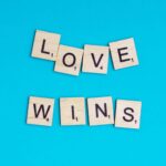 Carré bleu avec des lettres de Scrabble formant "Love Wins".